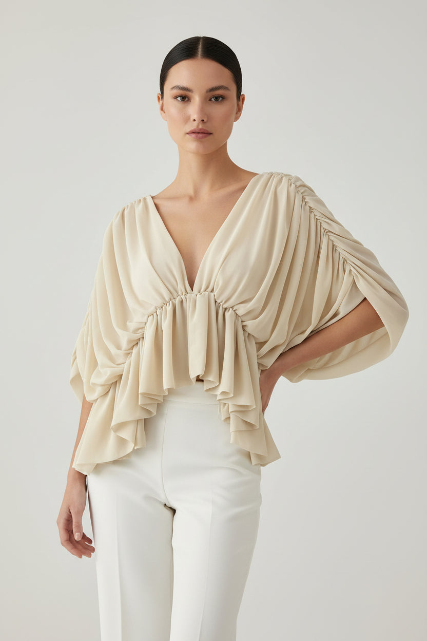 A beige draped off-the-shoulder blouse with a deep V-neckline, gathered elastic details, and cascading ruffles on a solid white background.